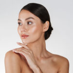 Beauty portrait of feminine young woman looking away and touching her nude shoulder isolated over white background